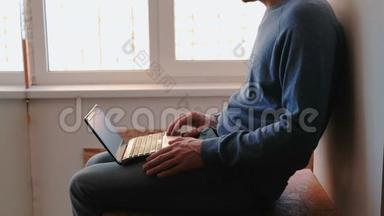 在笔记本电脑上工作。 一个面目全非的年轻人打开笔记本电脑，等待它启动和输入坐在上面的东西